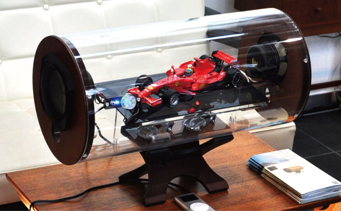 写真：スケルトンスピーカーのカスタムオーダー例、大型(アンプ内蔵型)レーシングカーの模型が入っている